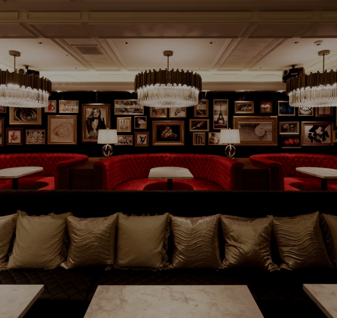 高級感あふれるラウンジの内装写真。赤いソファ、ゴールドの照明、アートが飾られた上質な空間で、落ち着いた雰囲気を演出。